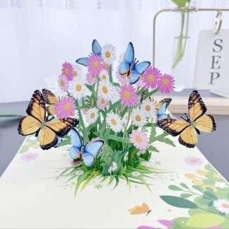 3D pop-up card featuring a vibrant bouquet of pink and white daisies with blue and orange butterflies perched on the petals
